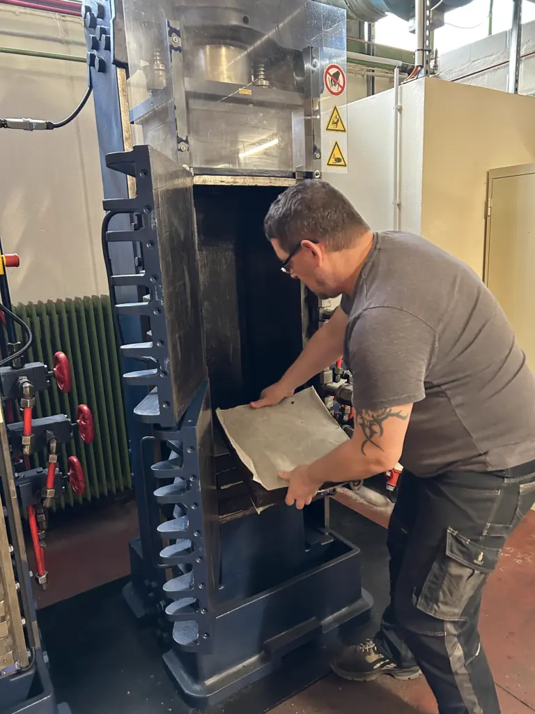 Die Szene zeigt Thomas Nitsche bei der entnhame eines Tabak-Cakes aus einer hydraulischen Tabakpresse